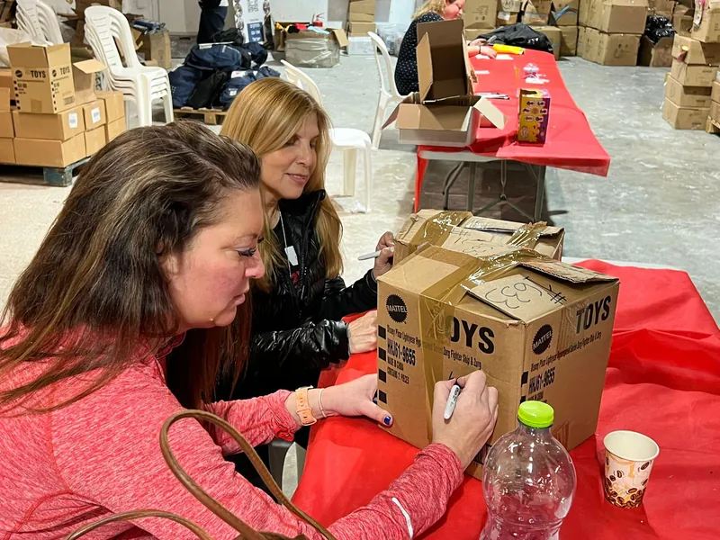 An AIC volunteer packs donated toys into a suitcase for a relief delivery to Israel, January 2024.