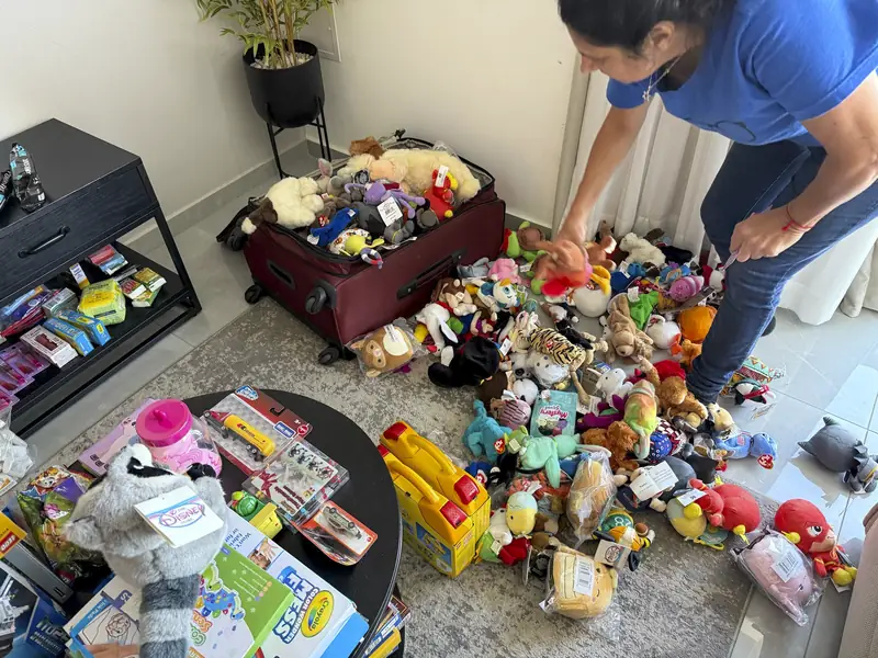 An AIC volunteer fills a suitcase with donated toys and stuffed animals for a relief delivery to Israel.