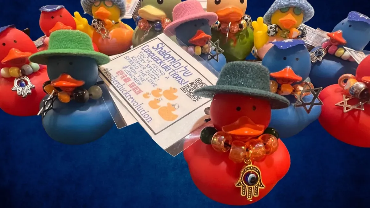 A heap of kosher ducks in knitted hats and bead necklaces with hamsa and Star of David charms, a Kosher Duck Revolution tag among them.